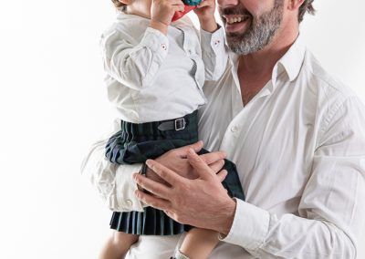 Fotografía infantil con Jan y Clara, creciendo con la familia papá y bebé con falda escocesa fotografia de familia elenirc