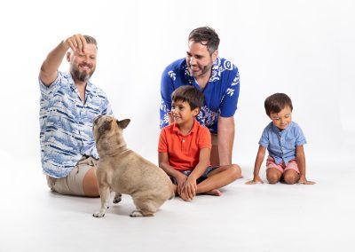 Familia con dos padres, dos hijos y perro durante sesión de fotografía de familia en estudio