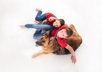 Fotografía de estudio de dos hermanos con un perro pastor aleman Yacko por Elena Rubio fotógrafa de familias con animales en mascotesdecolors y elenircfografia
