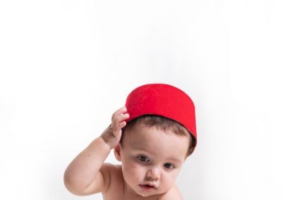 bebé de 8 meses gatea mientras quiere quitarse el sombrero típico marroquí fotografía de estudio de elena rubio en elenircfotografia