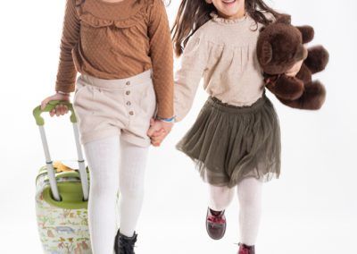 Sesiones de fotos en Barcelona: dos niñas corriendo en estudio con una maleta y un osito de peluche
