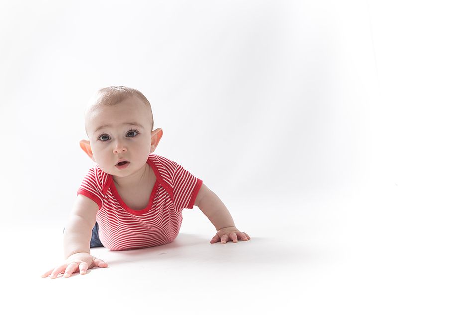 Bebé explorando el suelo durante una sesión de fotos en estudio, en plena etapa de movimiento