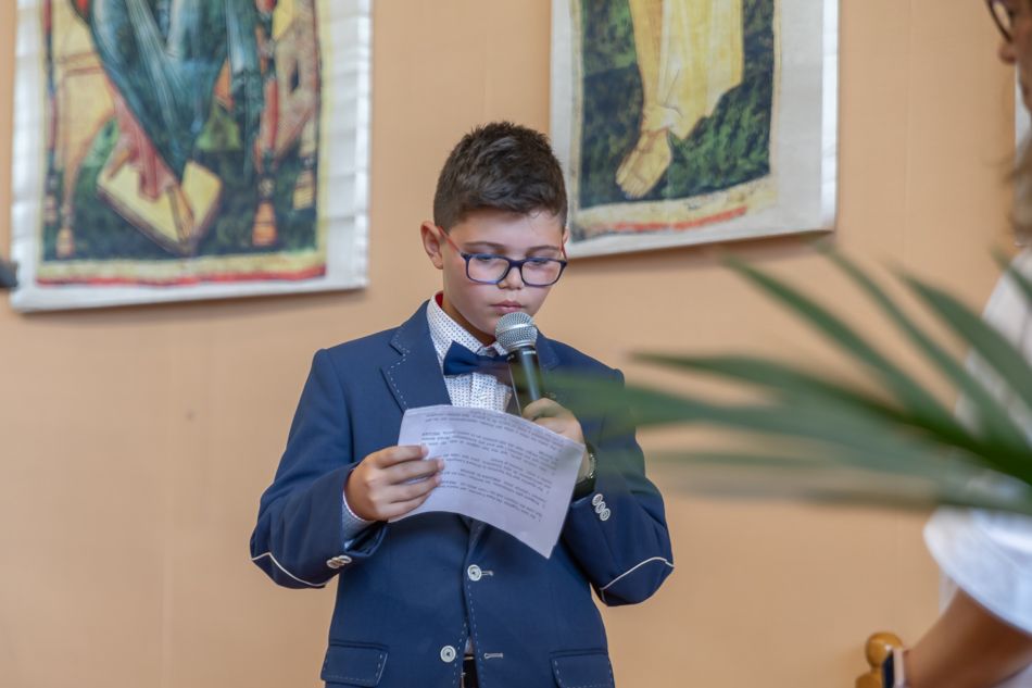 Un niño con traje de comunión sosteniendo un micrófono y la pregaria en la celebración de la comunión en Mollet foto elenircfotografia