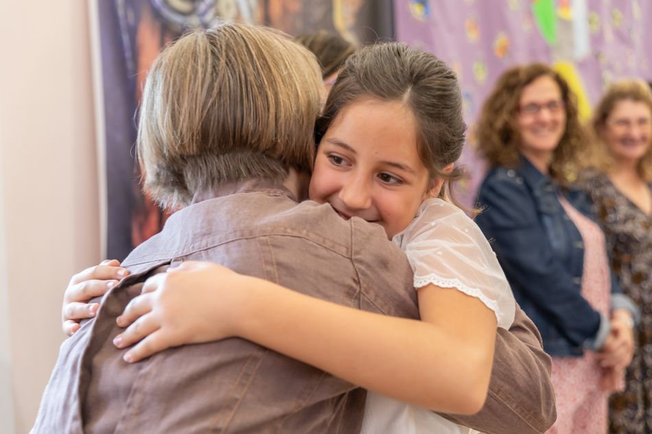 fotografía documental de celebraciones de comunión en Barcelona. elenircfotografia. Niña abraza a catequista