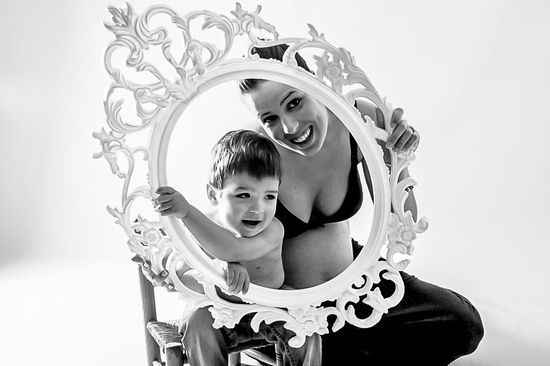 embarazo con hijo pequeño mirando a través de un espejo en estudio