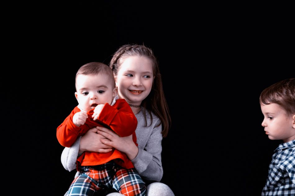 Hermanos compartiendo un momento cercano en sesión de fotografía de familia en estudio