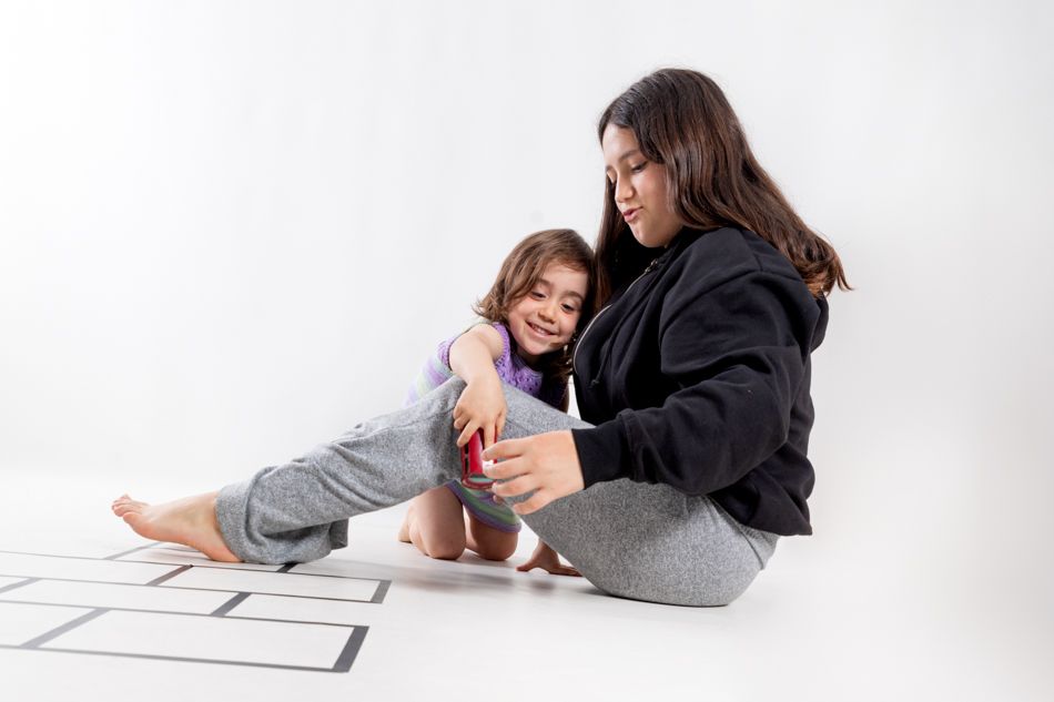 Niña y adolescente compartiendo un momento de juego durante una sesión de fotografía infantil en estudio en Mollet del Vallès, por Elenirc Fotografia.