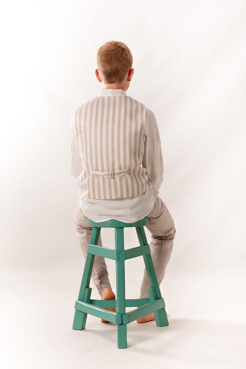 Fotografía de moda infantil en estudio, niño sentado de espaldas para marca de ropa