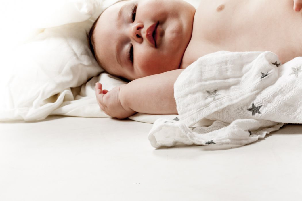 bebé descansando sobre cama con manta de estrellas