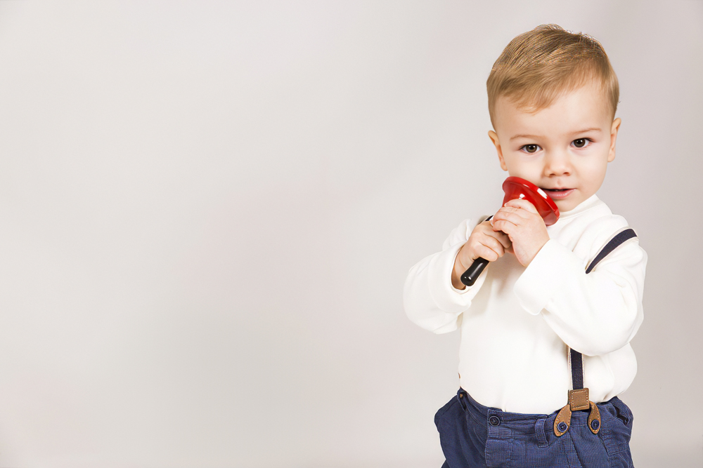 niño pequeño con campana de juguete en estudio