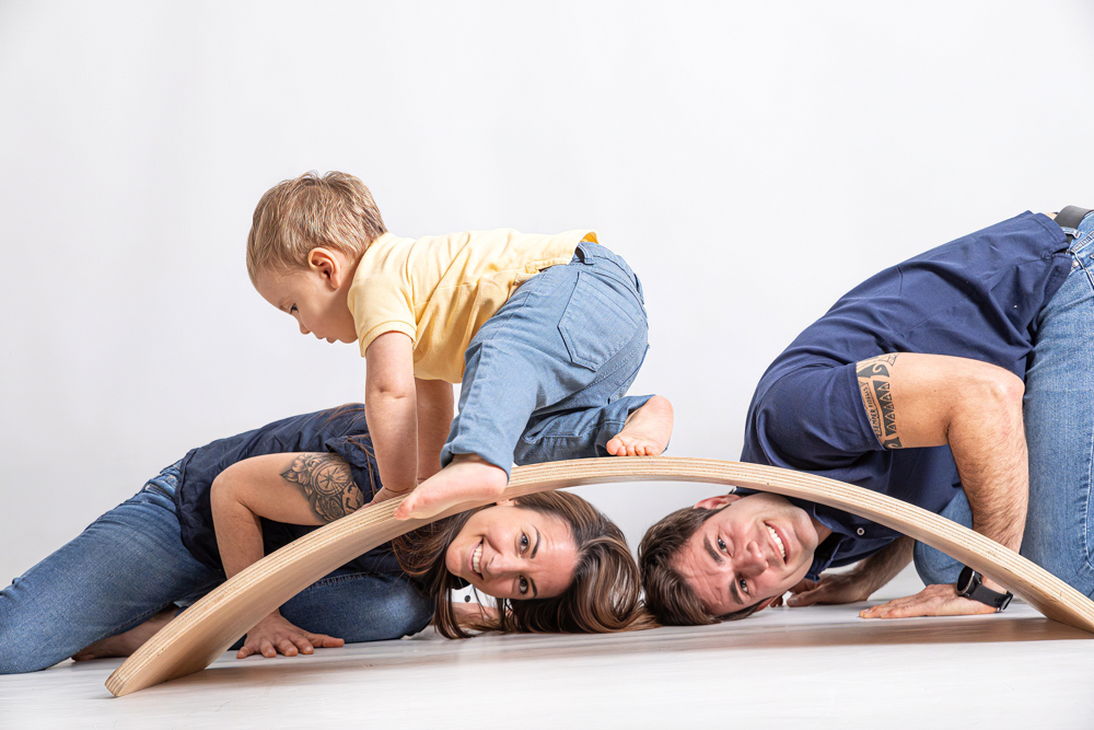 familia con bebé en sesión de primeros meses en estudio sobre tabla curva de madera