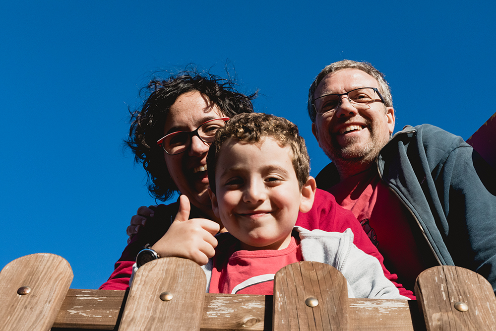 fotografía familia exterior Barcelona. Familia con niño sonriendo durante una sesión de fotos familiar en exterior en Barcelona