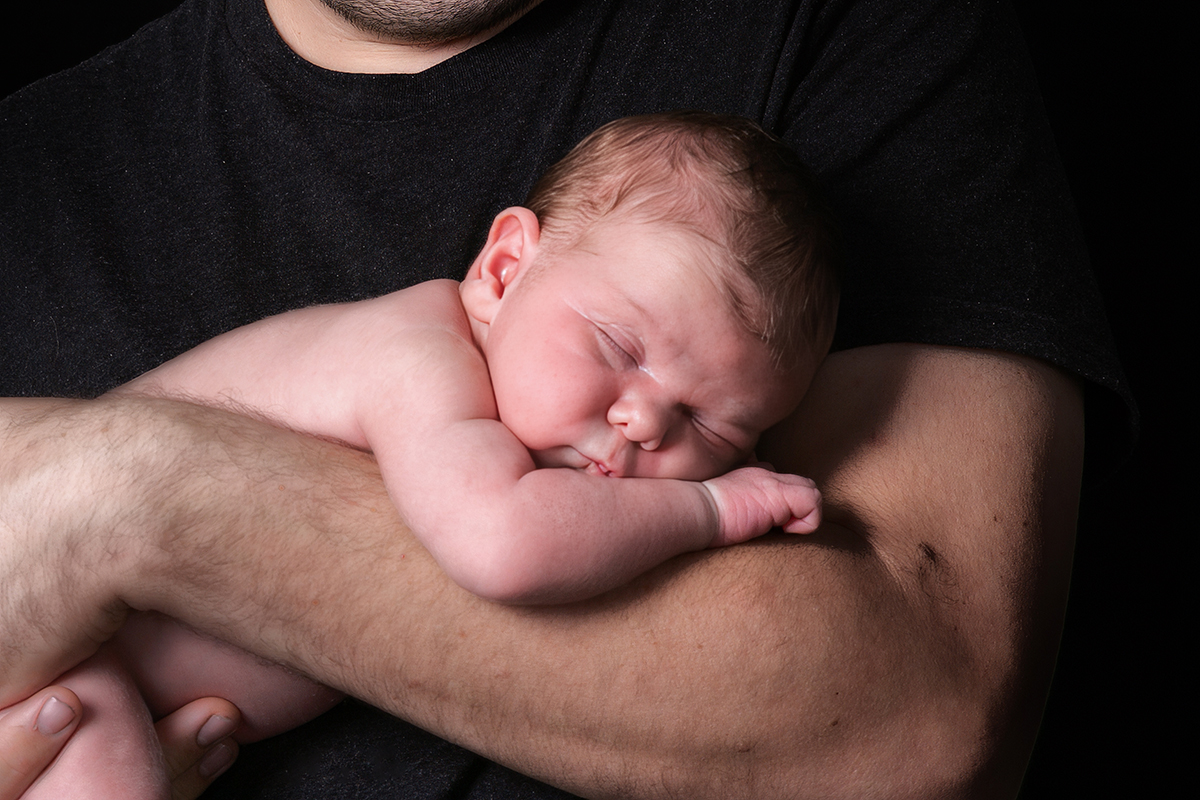 padre con su hijo recién nacido en brazos en sesión de fotografía newborn en Mollet del Vallès, Barcelona