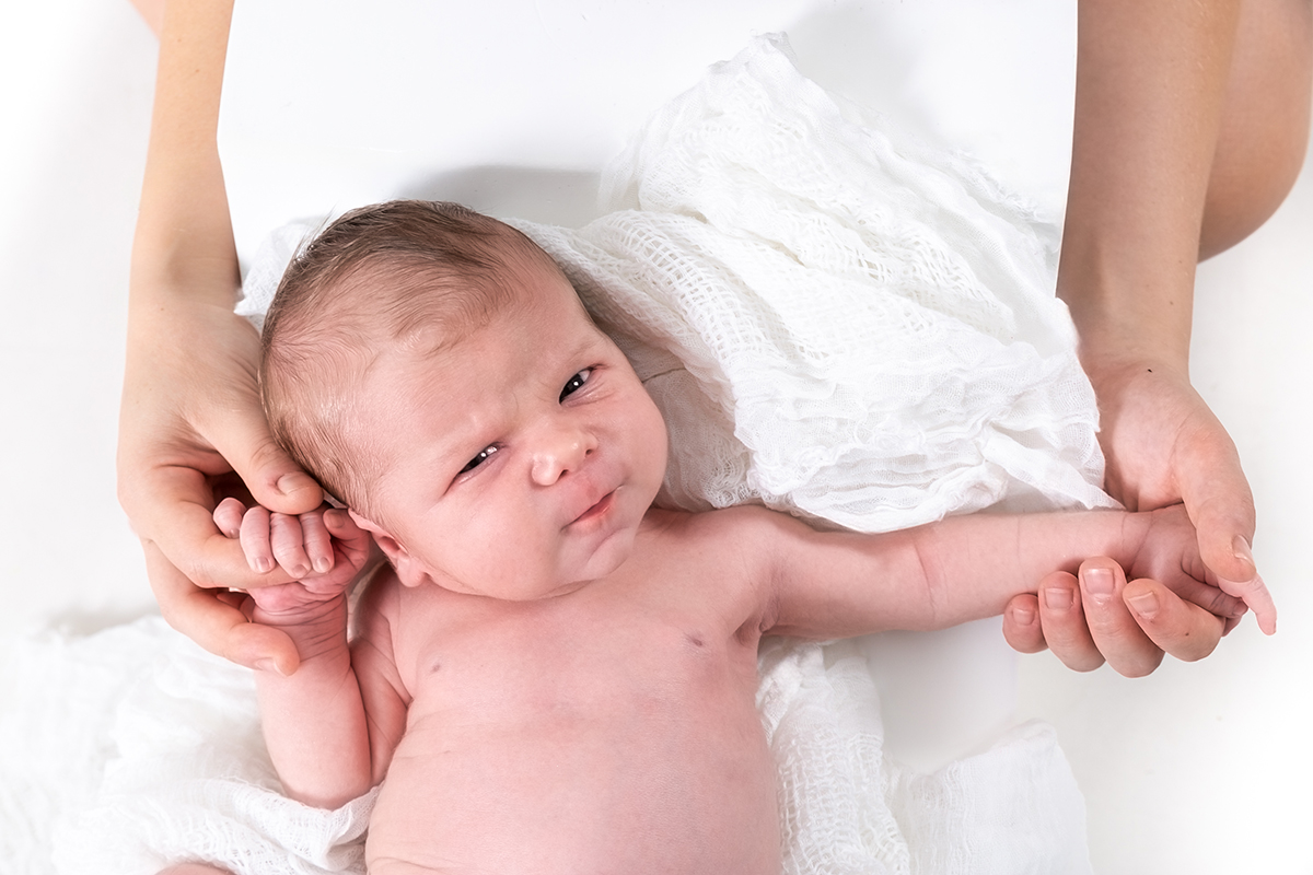 recién nacido con las manos de sus padres durante sesión newborn en estudio en Mollet del Vallès, Barcelona