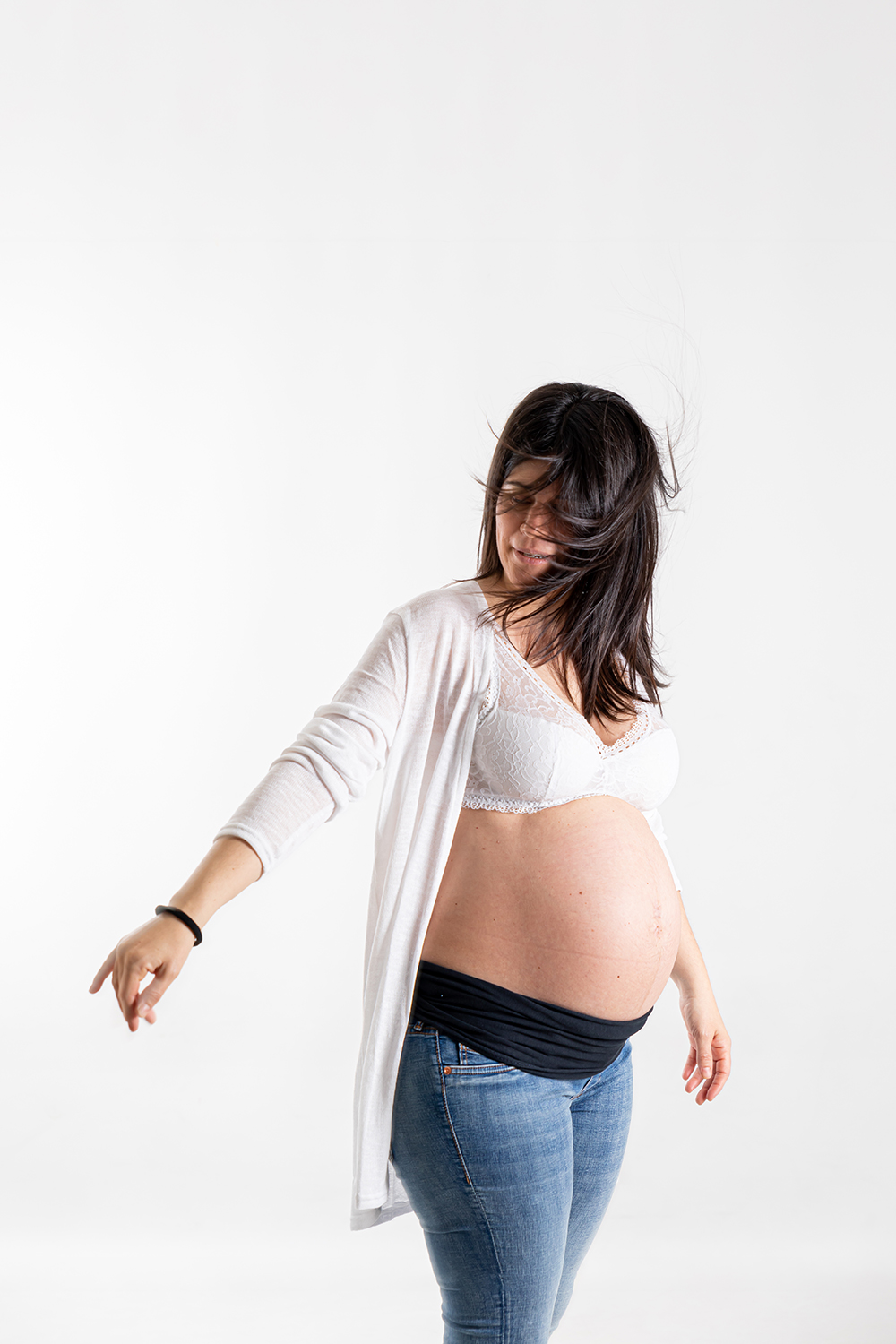 Mujer embarazada moviéndose con libertad durante una sesión de fotografía de embarazo en estudio en Mollet del Vallès, con una mirada natural, espontánea y centrada en su forma real de vivir este momento, por Elenirc Fotografia.