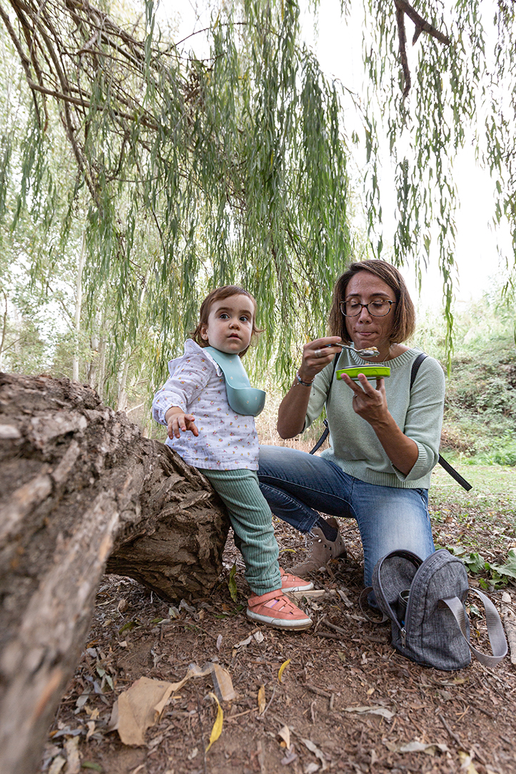Madre e hija compartiendo una pausa para comer durante una sesión de fotografía documental de familia en exterior en el Vallès Oriental, con una mirada natural y atenta a los momentos cotidianos, por Elenirc Fotografia.