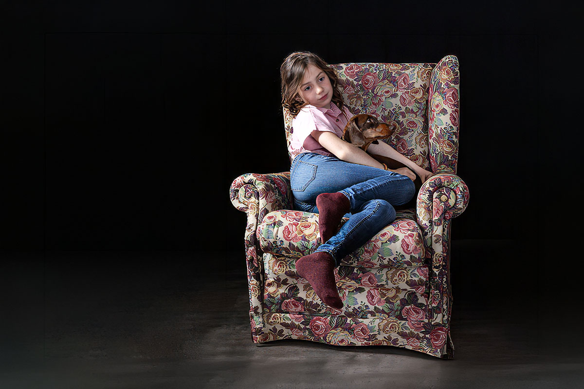 Elenirc Kids · Retrato infantil con mascota en Mollet del Vallès Niña abrazando a su perro en un sillón durante una sesión de fotografía Kids en estudio