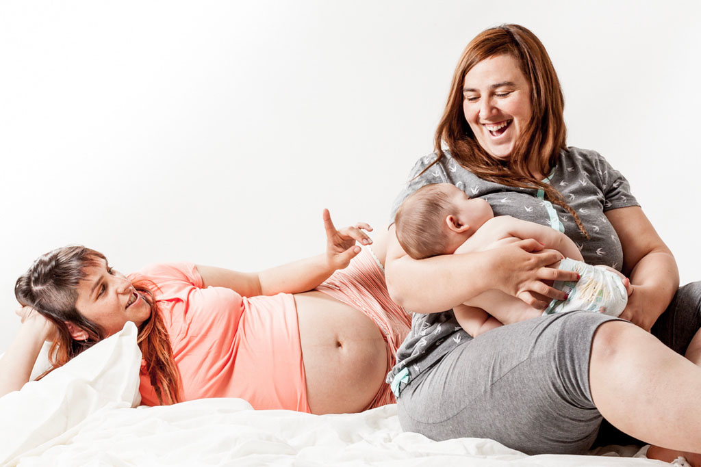 Embarazo en familia en estudio Fotografía de embarazo en familia durante una sesión en estudio dos mamás
