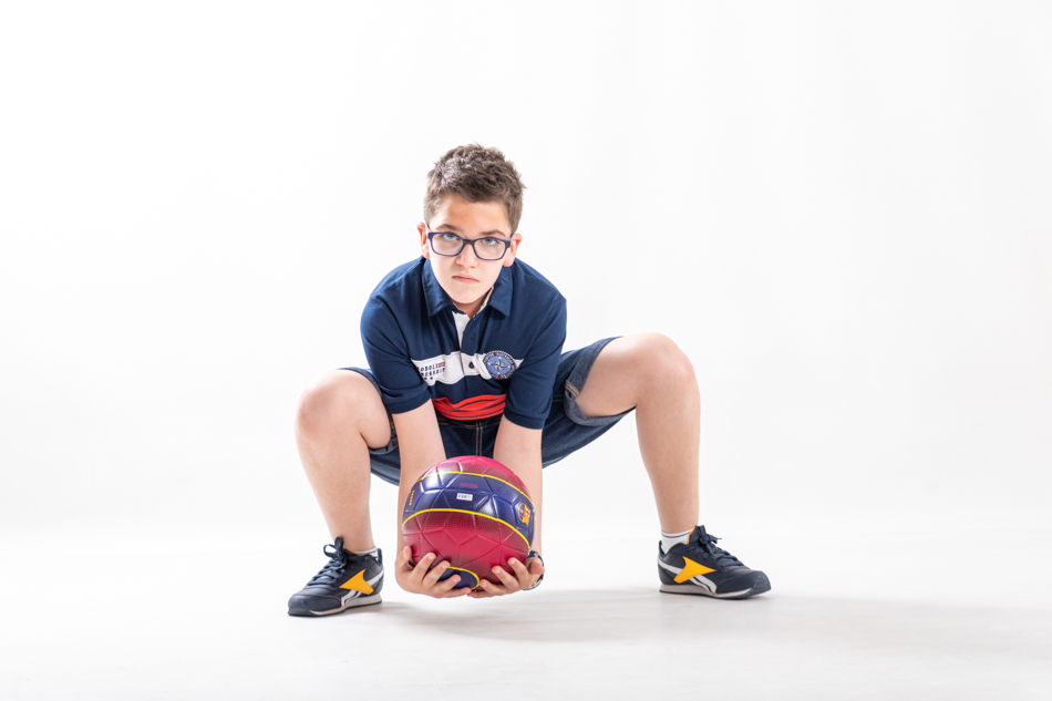 Niño con balón oficial del Barça en una sesión de retrato deportivo infantil en estudio
