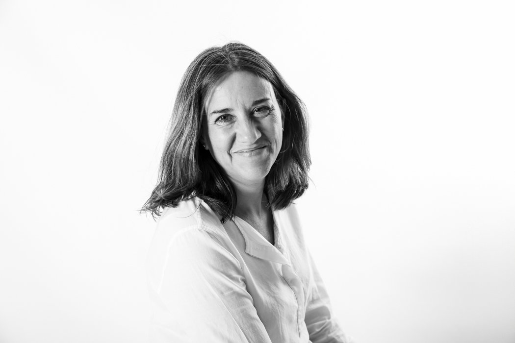 Retrato de una profesional con camisa blanca, mirando a cámara y sonriendo durante una sesión de fotos para su página web, por Elena Rubio · Elenirc Fotografia.