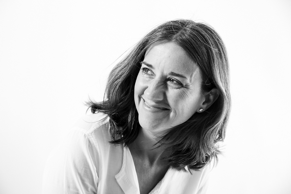 Primer plano de una profesional sonriendo y mirando hacia un lado durante una sesión de fotos para su página web, en blanco y negro, por Elena Rubio · Elenirc Fotografia.