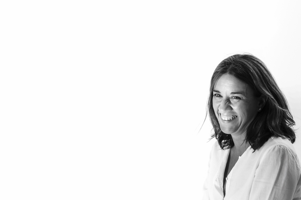 Retrato de una profesional sonriendo, situada a la derecha del encuadre sobre fondo blanco, durante una sesión de fotos para su página web, por Elena Rubio · Elenirc Fotografia.