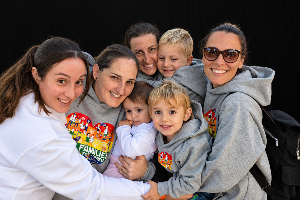 Familias LGTBI+ con bebés, niños y niñas reunidas en un abrazo colectivo durante la Castañada de FLG. Retrato de diversidad familiar de Elena Rubio · elenirc.