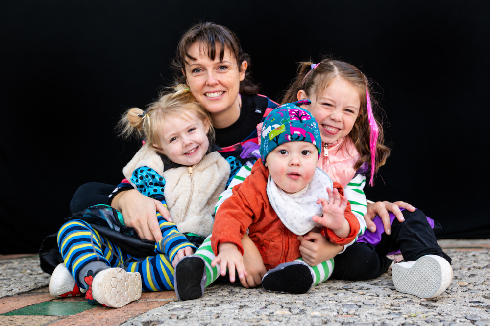 Una mamá con sus tres hijos compartiendo juegos y sonrisas durante la Castañada de FLG · Famílies LGTBI+. Retrato de diversidad familiar de Elena Rubio · elenirc.